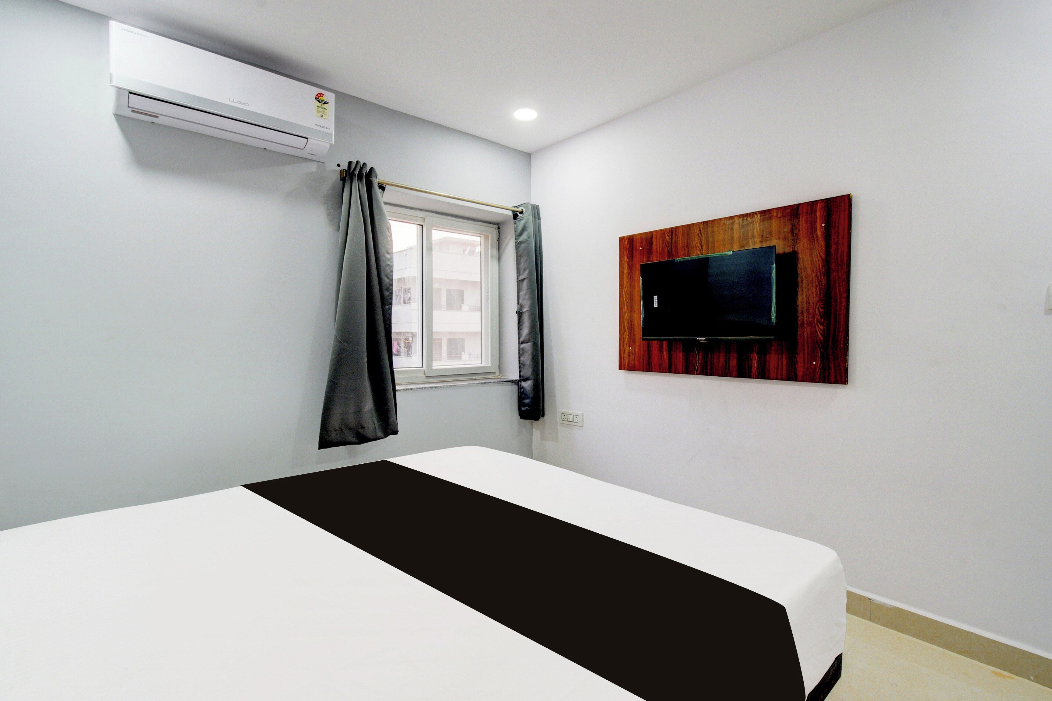 Une chambre d’hôtel équipée d’un lit, d’un téléviseur fixé au mur et d’un appareil de climatisation.