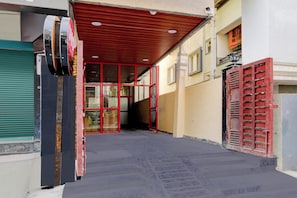 A narrow corridor with a red metal gate and a green shutter door. - Hotel O Vega (Hyderabad)