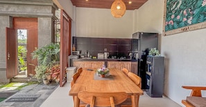 A modern kitchen with a wooden dining table, a black refrigerator, and a tiled backsplash. - Villa Laku Singakerta with Kitchenette (Gianyar)