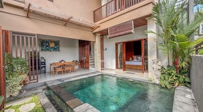 A two-story building with a swimming pool, wooden furniture, and tropical plants. - Villa Laku Singakerta with Kitchenette (Gianyar)