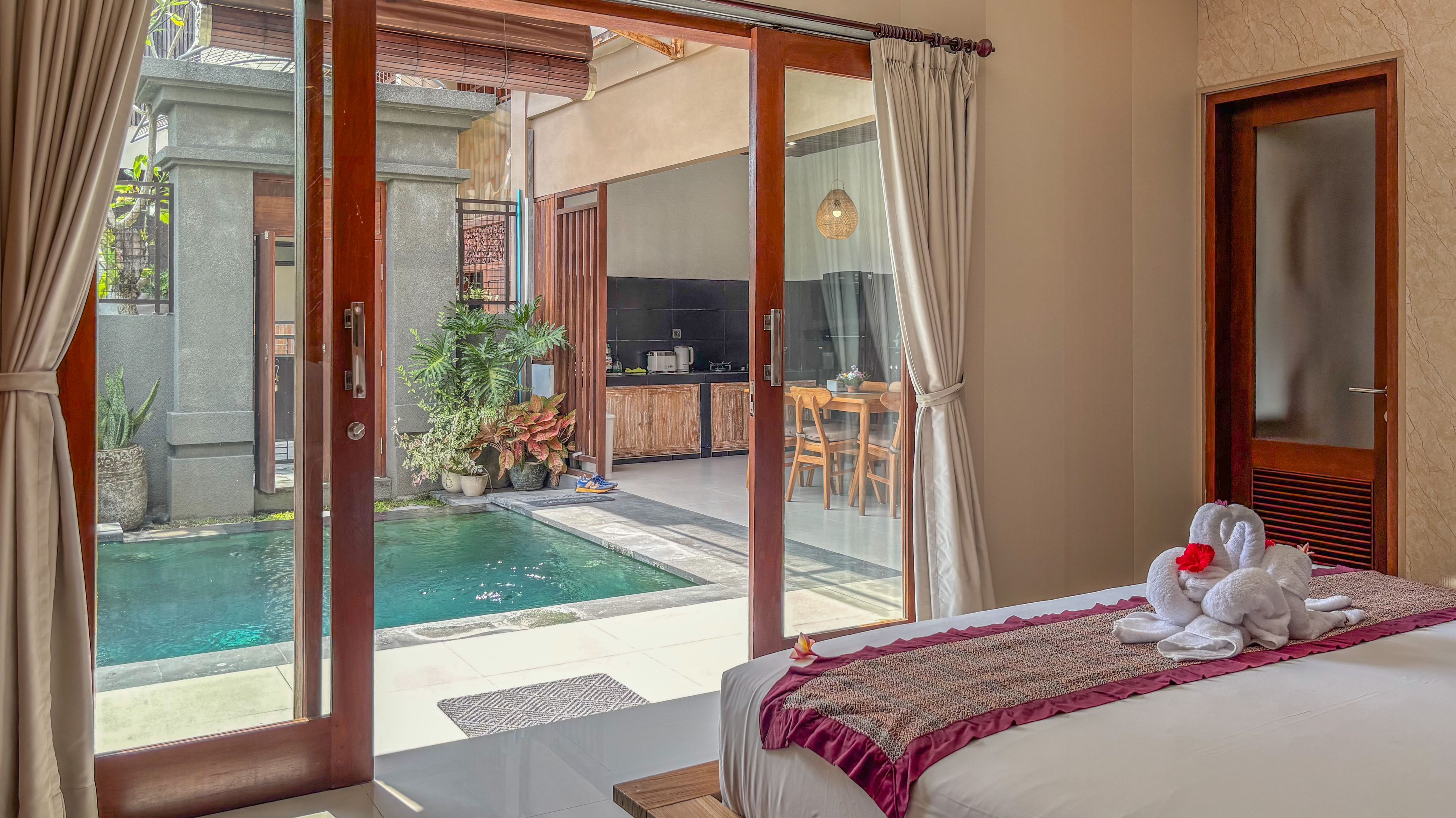 A hotel room with a bed, a view of a pool, and a dining area.