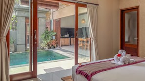 A hotel room with a bed, a view of a pool, and a dining area. - Villa Laku Singakerta with Kitchenette (Gianyar)