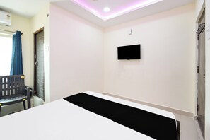 A room with a bed, a flat-screen TV mounted on the wall, and a chair. - HOTEL O SVR GRAND (Hyderabad)