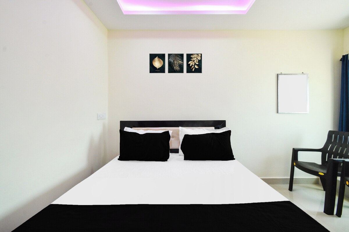 A hotel room with a bed, a chair, and a wall-mounted whiteboard.