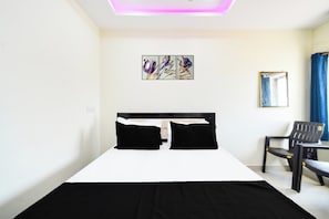 Habitación de hotel con cama, una silla, un escritorio y un espejo en la pared.