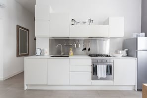 Eine moderne Küche mit weißen Schränken, einer Edelstahl-Spüle, einem Gasherd und einem Backofen.