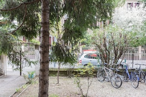 Ein Parkplatz mit Fahrrädern, einem Auto und einem Baum.