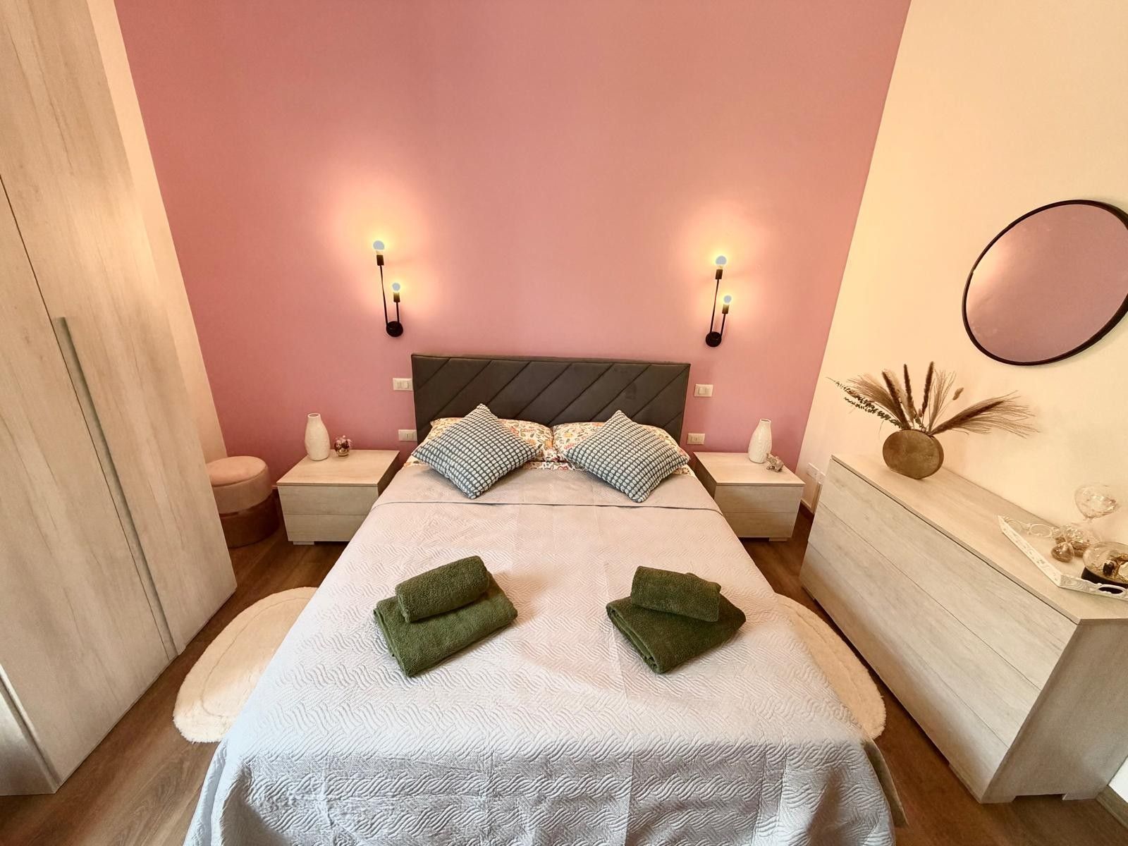 A bedroom with a bed, two bedside tables, a dresser, and wall-mounted lights.