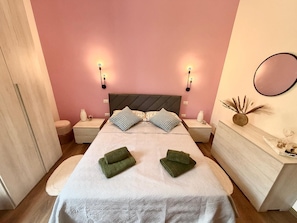 Ein Schlafzimmer mit einem Bett, zwei Nachttischen, einer Kommode und Wandleuchten.