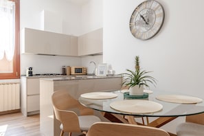 Eine moderne Küche mit einem Glastisch, Stühlen und einer dekorativen Uhr.