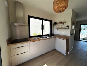 Een moderne keuken met een groot raam, een roestvrijstalen afzuigkap en houten aanrecht.