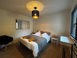 Een slaapkamer met een bed, nachtkastjes, een bureau en een stoel.
