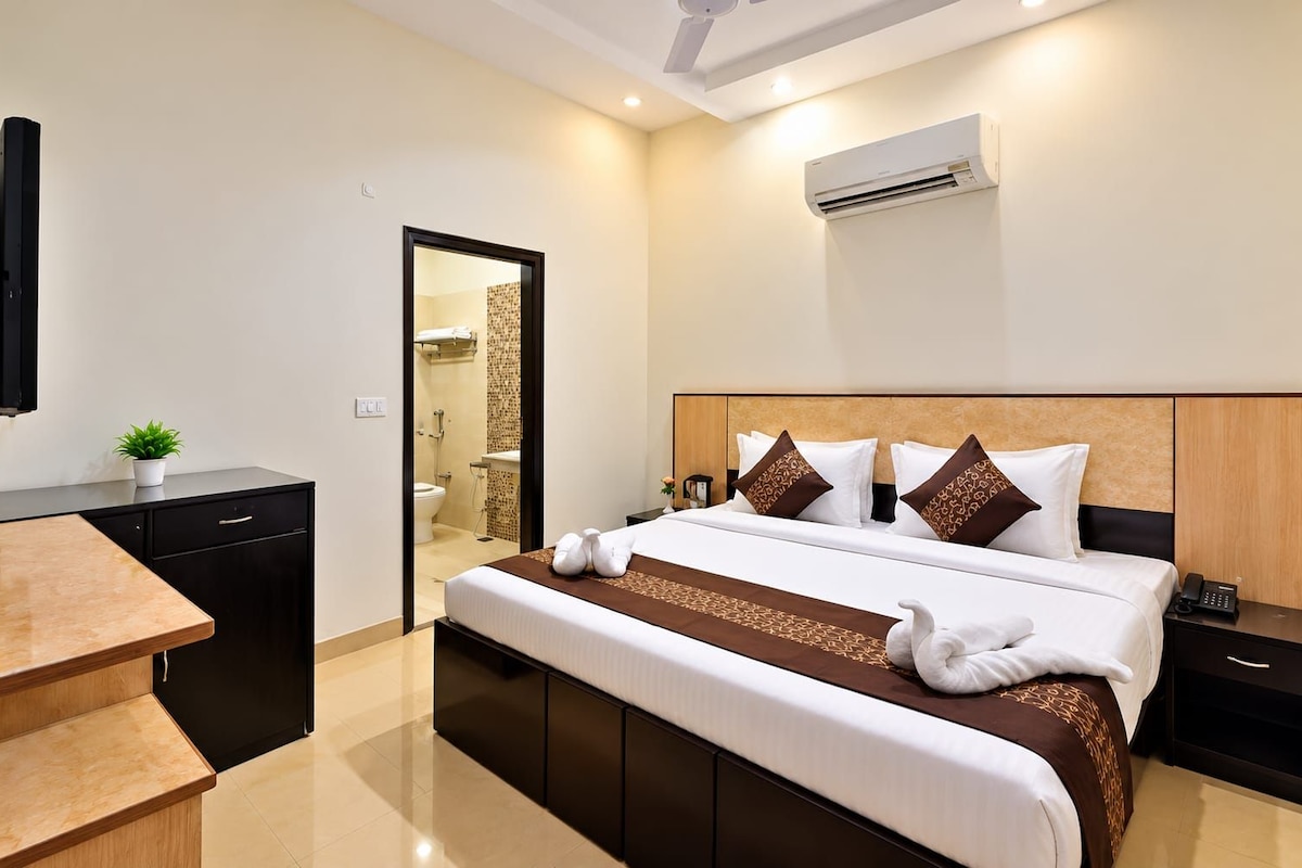 A hotel room with a bed, bedside table, and a desk with a chair.
