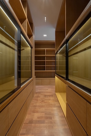 Un couloir doté d’étagères en bois et de vitrines, qui mène à un escalier.