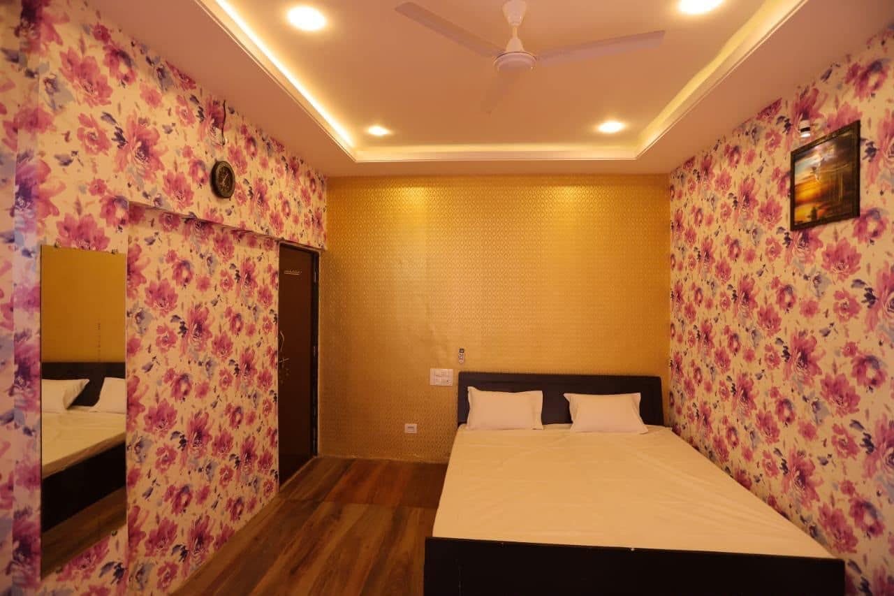 A hotel room with floral wallpaper, a bed with white bedding, a ceiling fan, and recessed lighting.