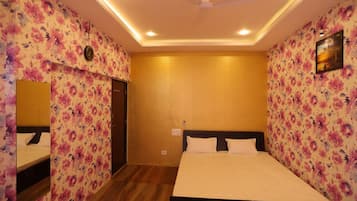 A hotel room with floral wallpaper, a bed with white bedding, a ceiling fan, and recessed lighting.