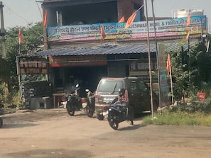 A building with multiple signs, including one for a hotel and family restaurant, and another for a business. There are motorcycles parked in front. - Rajeshwari Hotel and Family Restaurant (Mandu)