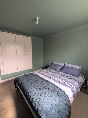 Un dormitorio con cama, armario y mesita de noche.