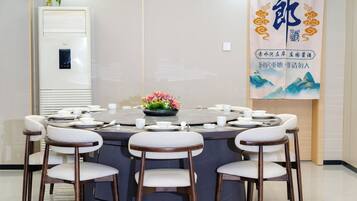 Un salón de conferencias con una mesa redonda, sillas blancas y un centro de mesa floral.