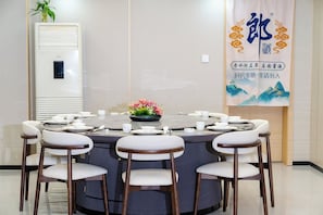 A conference room with a round table, white chairs, and a floral centerpiece. - Ruba Hotel (Phnom Penh)