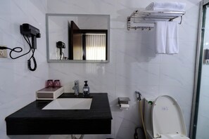 A bathroom with a black sink, a mirror, a hairdryer, a towel rack, and a toilet. - Ruba Hotel (Phnom Penh)