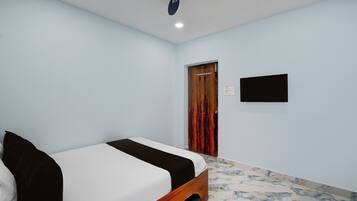 A bedroom with a bed, a ceiling fan, a door, and a wall-mounted TV.