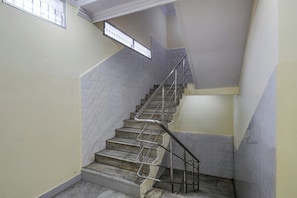 A staircase with metal handrails, marble steps, and a plain wall with a window. - Hotel O New Star Lodge (Hyderabad)