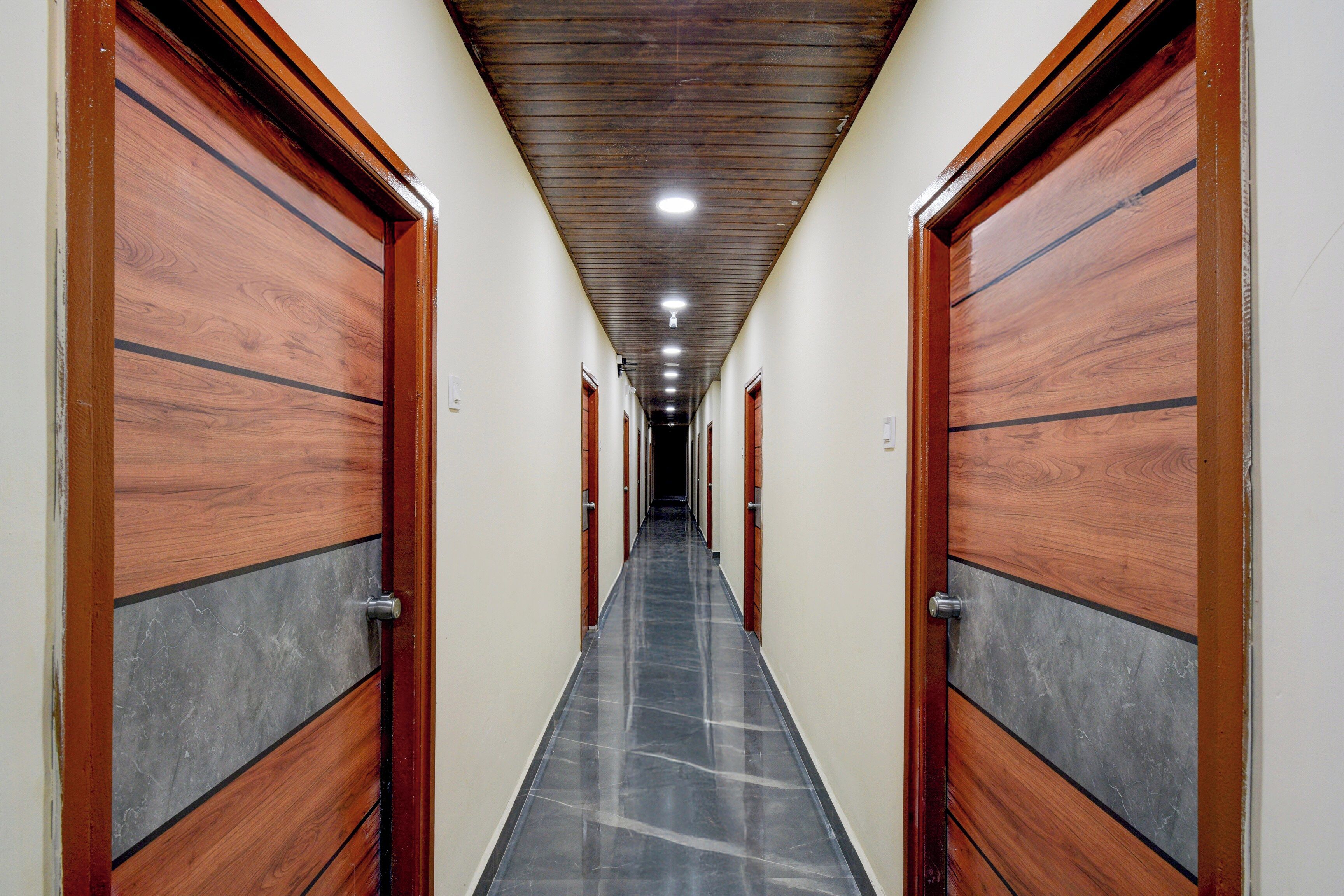 A hallway with wooden doors and a tiled floor, leading to multiple rooms.