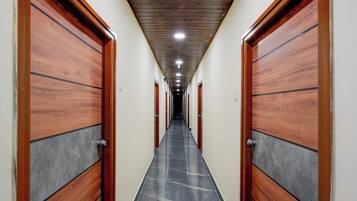 A hallway with wooden doors and a tiled floor, leading to multiple rooms.