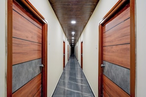 A hallway with wooden doors and a tiled floor, leading to multiple rooms. - Hotel O Nova Comfort Inn (Hyderabad)