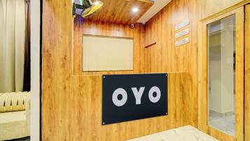 A reception area with a wooden wall, a sign reading 'OYO', and a glass door.