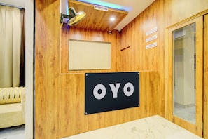 A reception area with a wooden wall, a sign reading 'OYO', and a glass door. - Super Hotel O PNR CONTINENTAL MOOSAPET (Hyderabad)