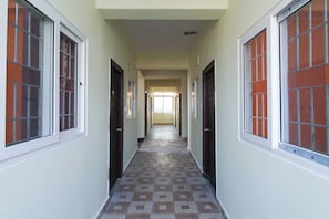 A corridor with doors on both sides, leading to a bright room at the end. - Hotel O S V Residency (Hyderabad)