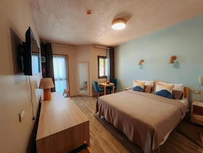Habitació d'hotel amb llit, escriptori, cadira, televisió i finestra.