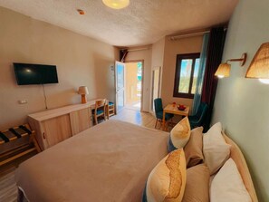 Una habitació d'hotel amb un llit, una taula de treball, una televisió i una finestra.