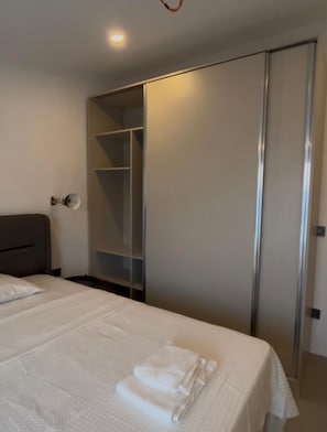 Habitació d'hotel amb un llit, un armari i una taula de nit.