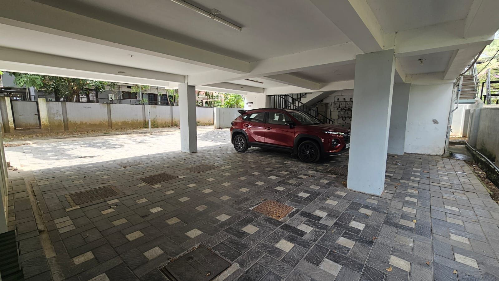 Uma área de estacionamento coberta com um carro vermelho estacionado sob um toldo branco.