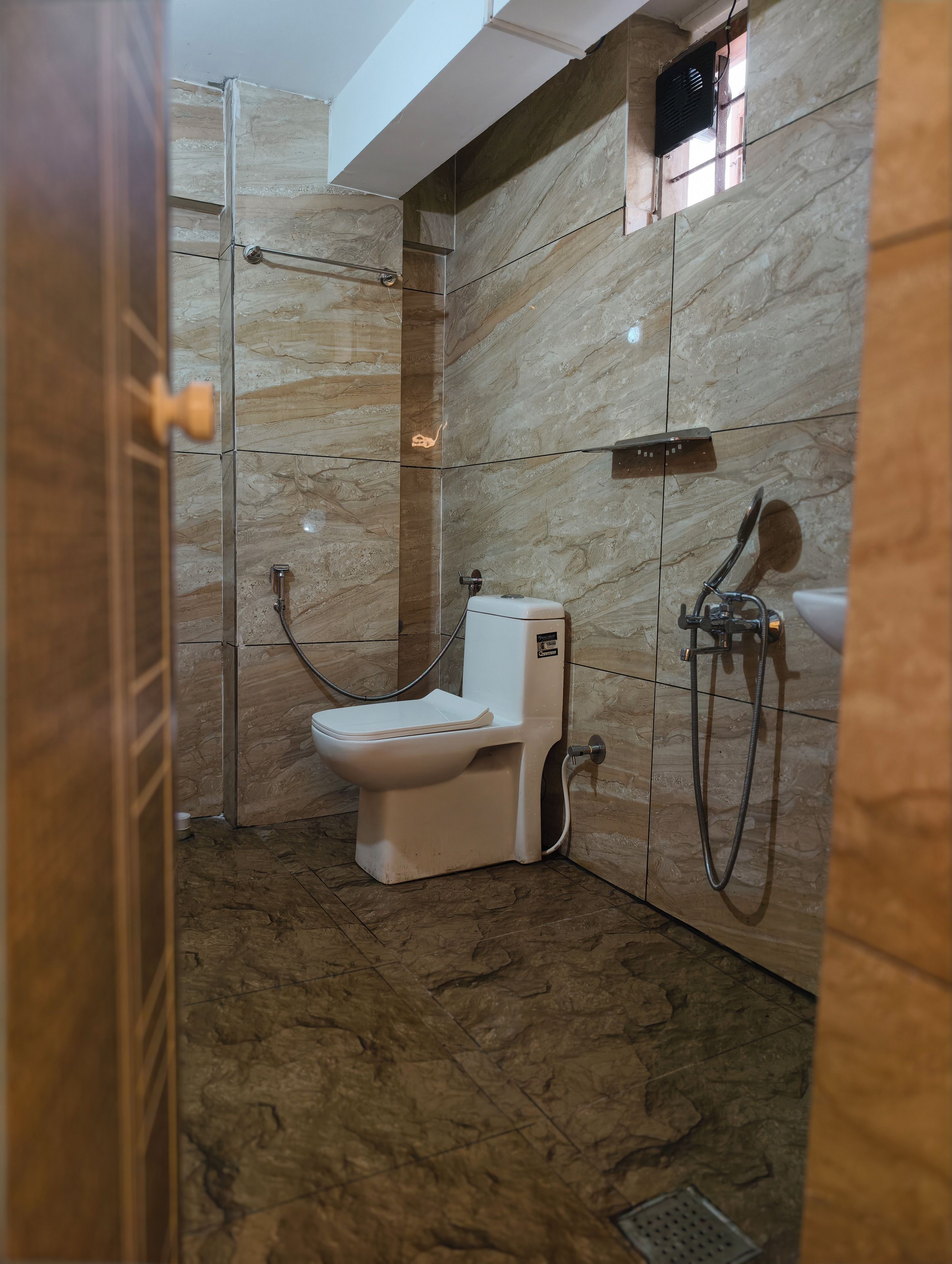 A bathroom with a toilet, shower, and a wall-mounted sink.