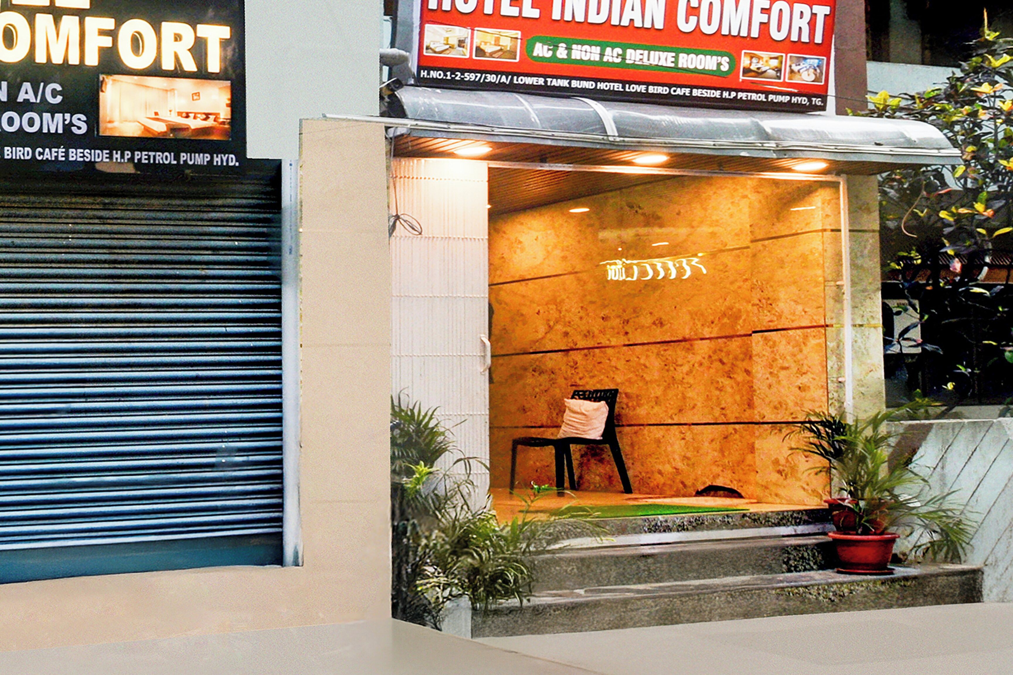A hotel entrance with a closed shutter on the left and a sign for 'Hotel Indian Comfort' above the door.