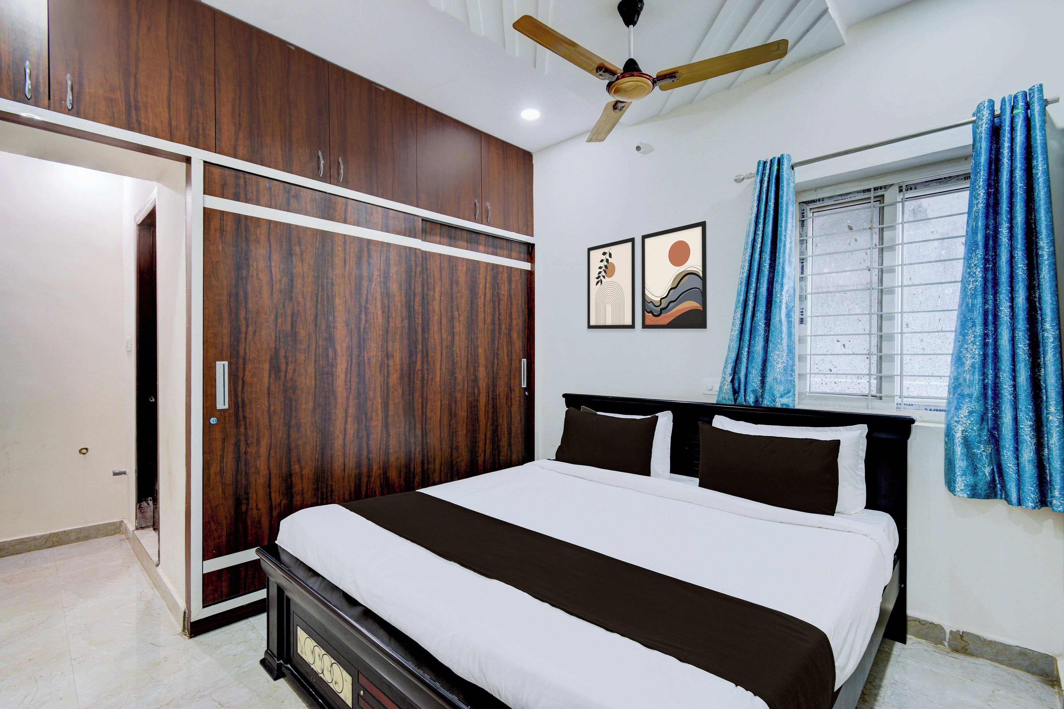 A bedroom with a bed, a wardrobe, a ceiling fan, and a window with curtains.