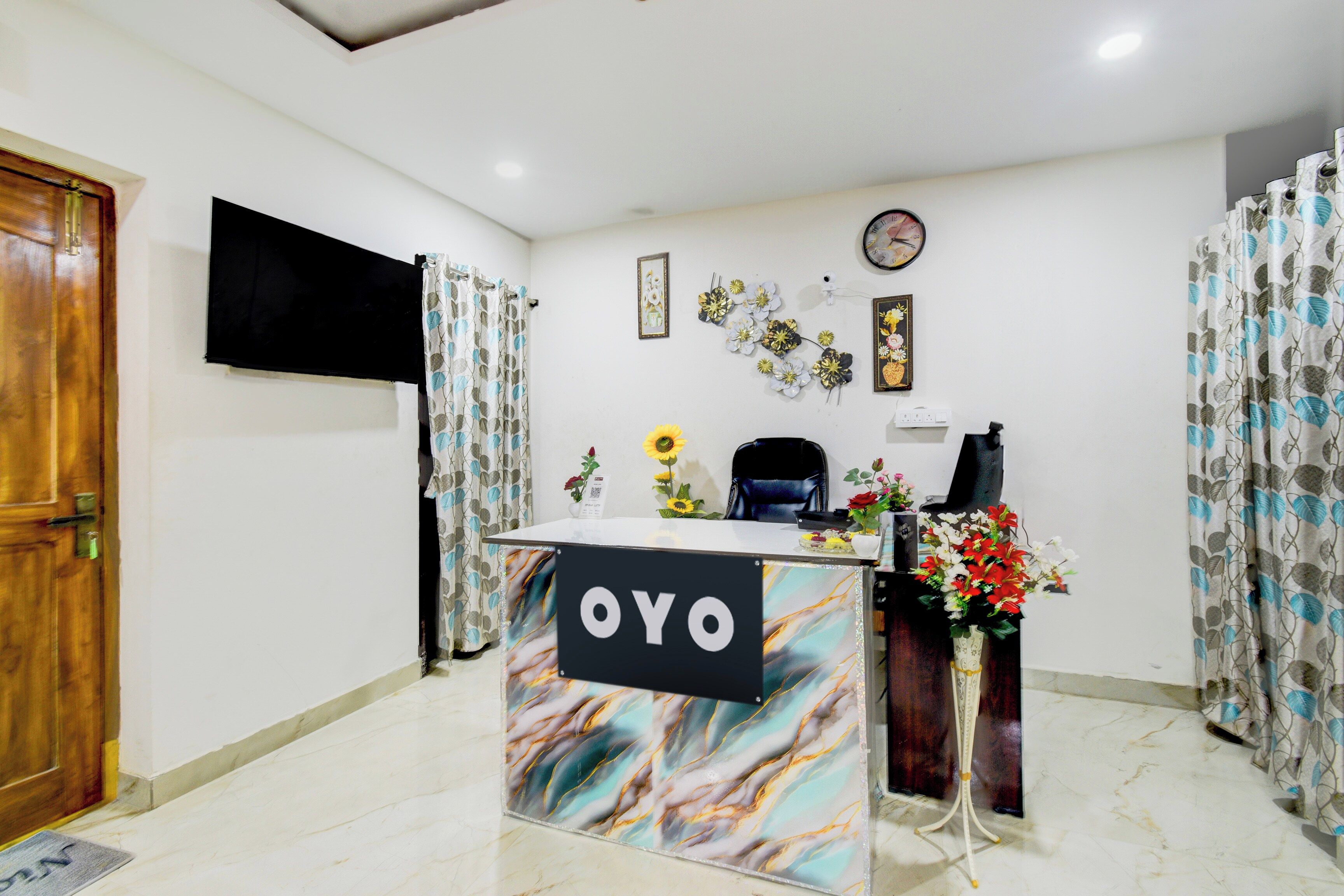 A reception area with a marble-patterned desk, a clock on the wall, and floral decorations.