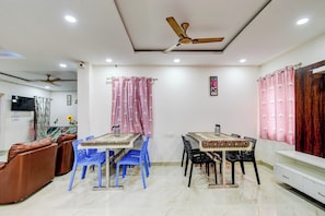 A dining area with a table and chairs, a ceiling fan, and a television on the wall. - Hotel O RR GRAND STAY (Hyderabad)