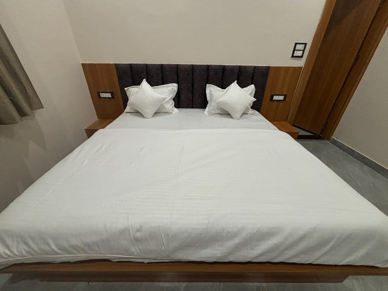 Una habitación de hotel estándar con una cama individual, dos almohadas, un cabecero y una mesita de noche.