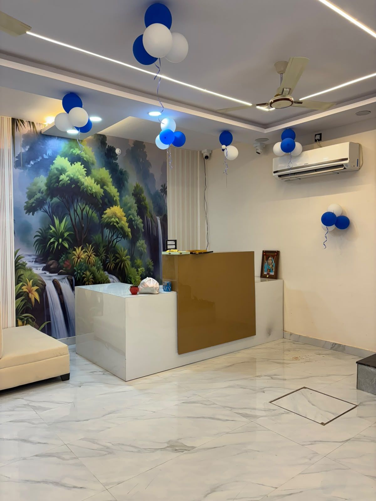 Un área de recepción con un mural, un mostrador de recepción y un ventilador de techo.