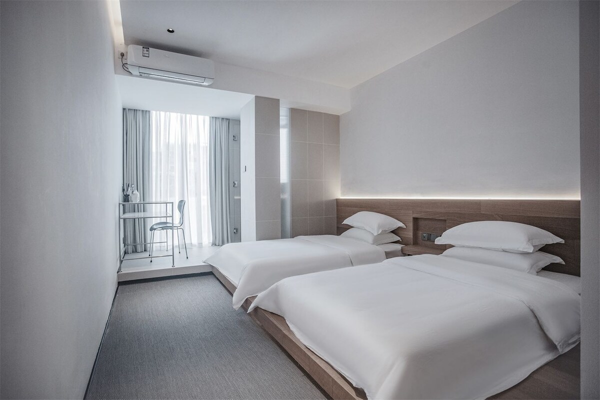 Ein Hotelzimmer mit zwei Betten, einer Sitzecke mit einem Sessel und Blick ins Freie.