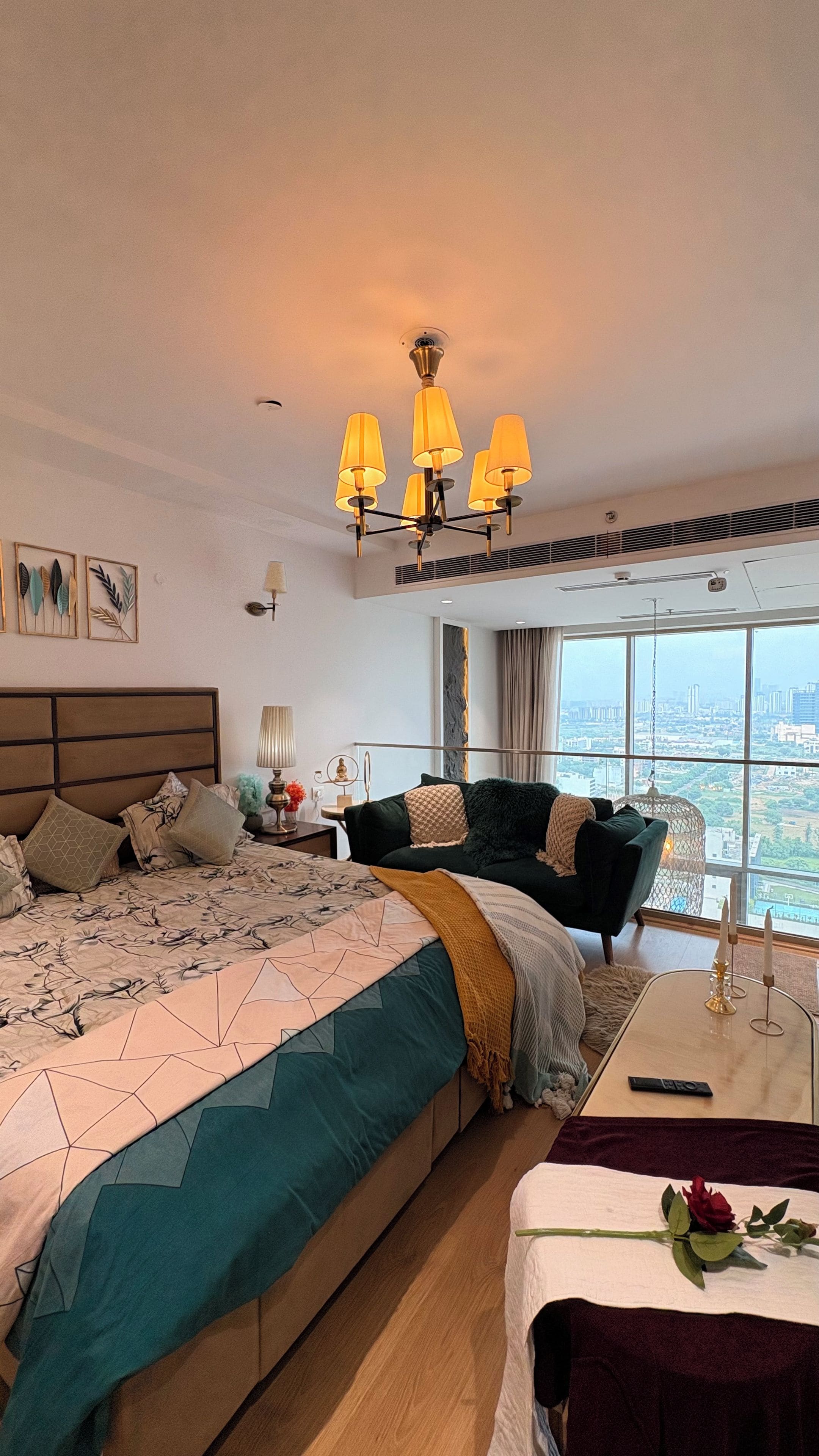 A modern bedroom with a large bed, a view of the city, and a chandelier.