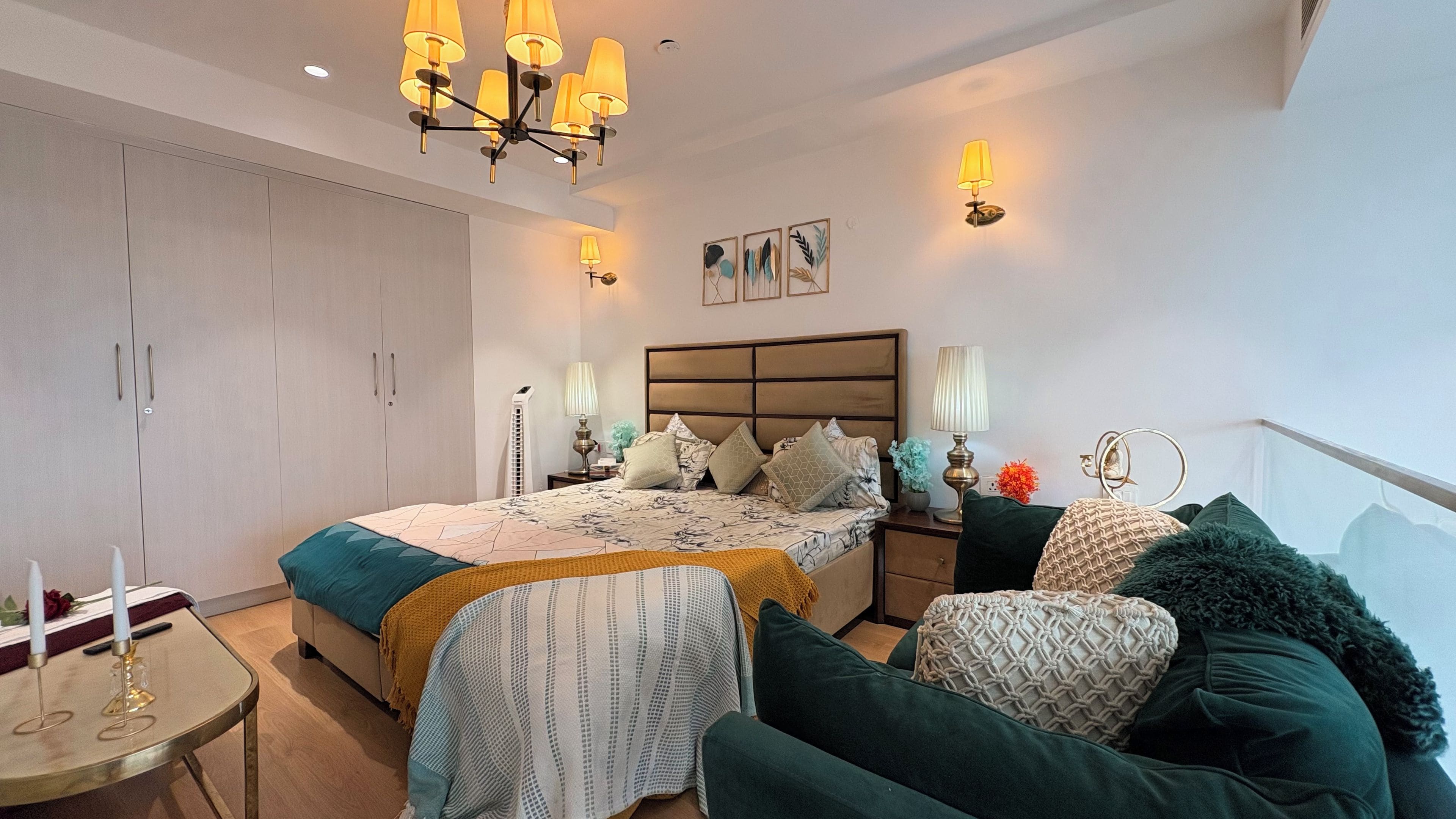 A bedroom with a bed, bedside tables, a wardrobe, and a chandelier.