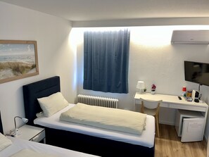 Une chambre d’hôtel comprenant un lit, une table de chevet, un bureau, une chaise et un téléviseur.