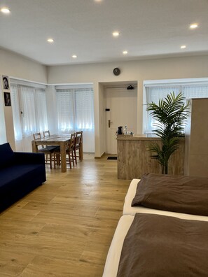 Une pièce moderne et bien éclairée, avec une table à manger en bois, des chaises, un canapé et un lit.