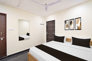 A hotel room with a bed, a mirror, a door, and three framed artworks on the wall. - Hotel O Nampally Grand (Hyderabad)
